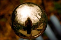 a person's reflection in a gold ball
