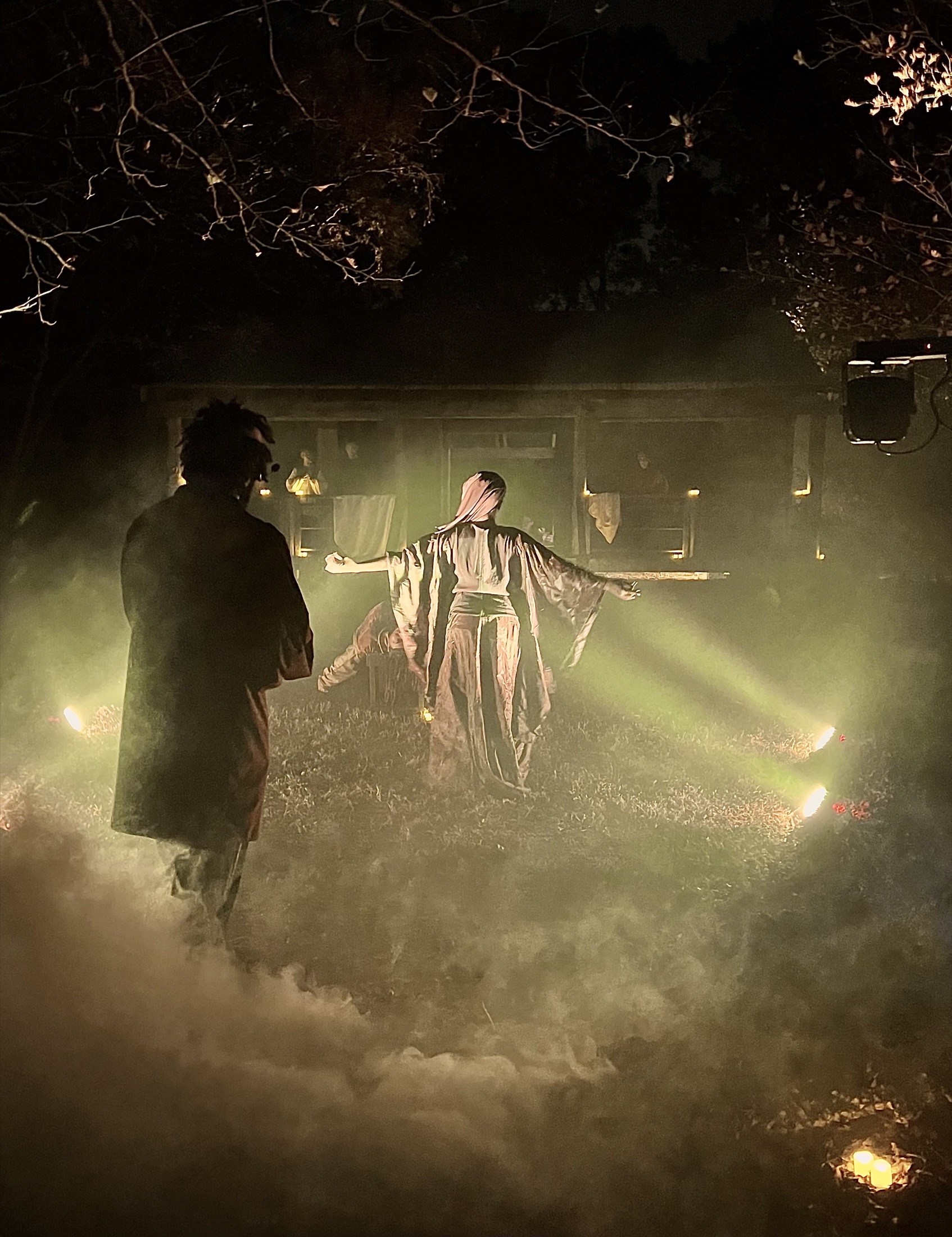 Two performers face one another in a blue-lit scene
