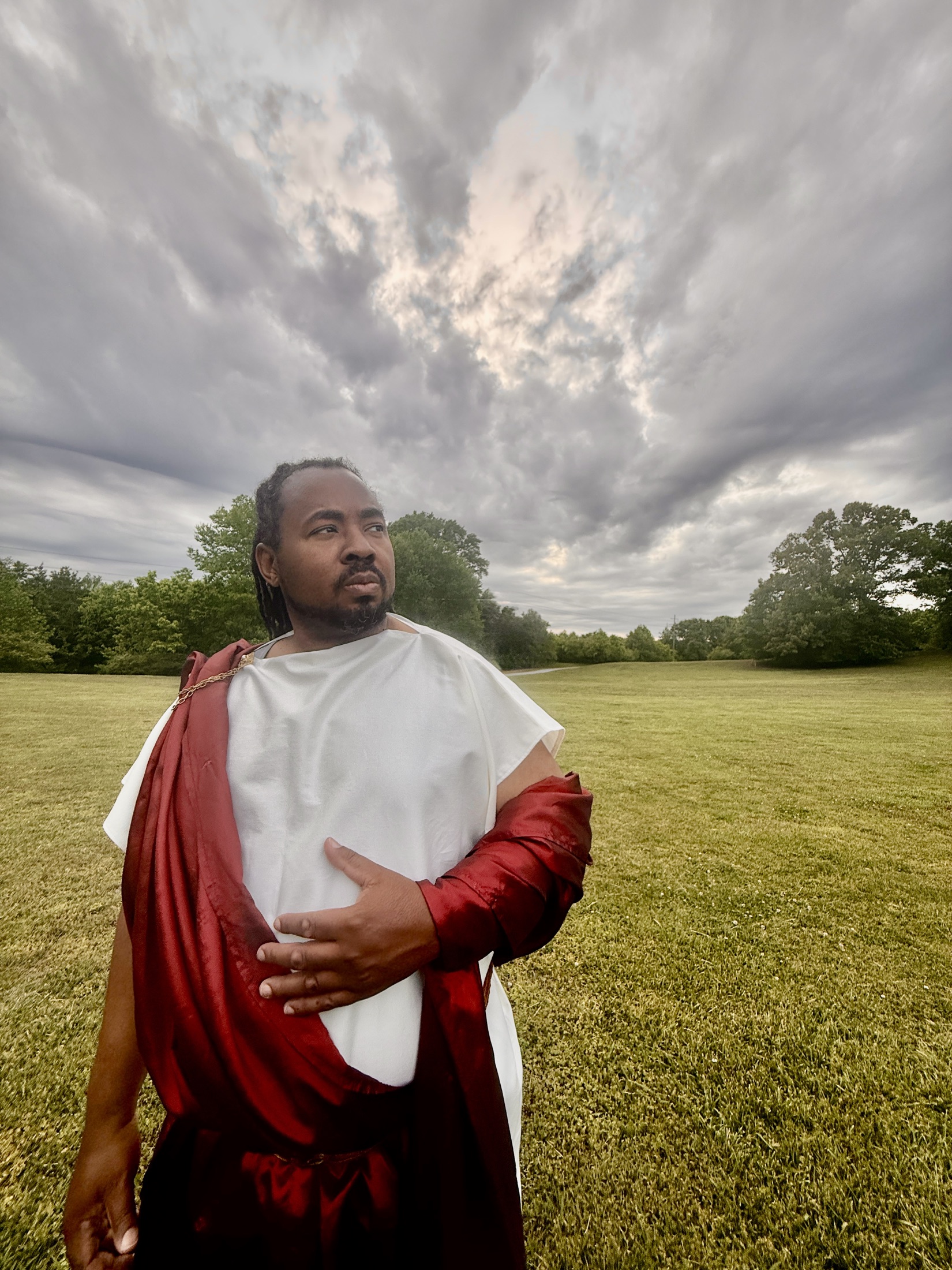 Othello stands beneath a dramatic evening sky