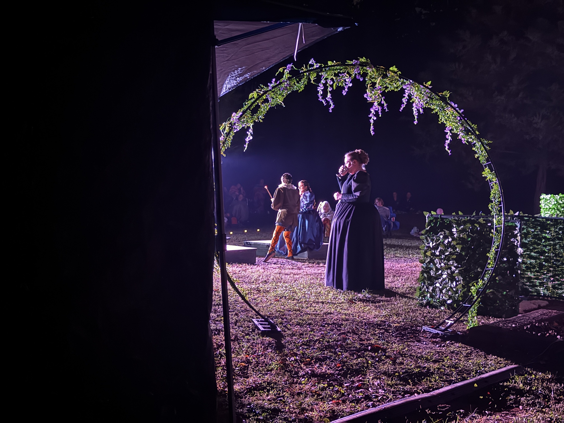 A performer watches the stage from behind a stone arch